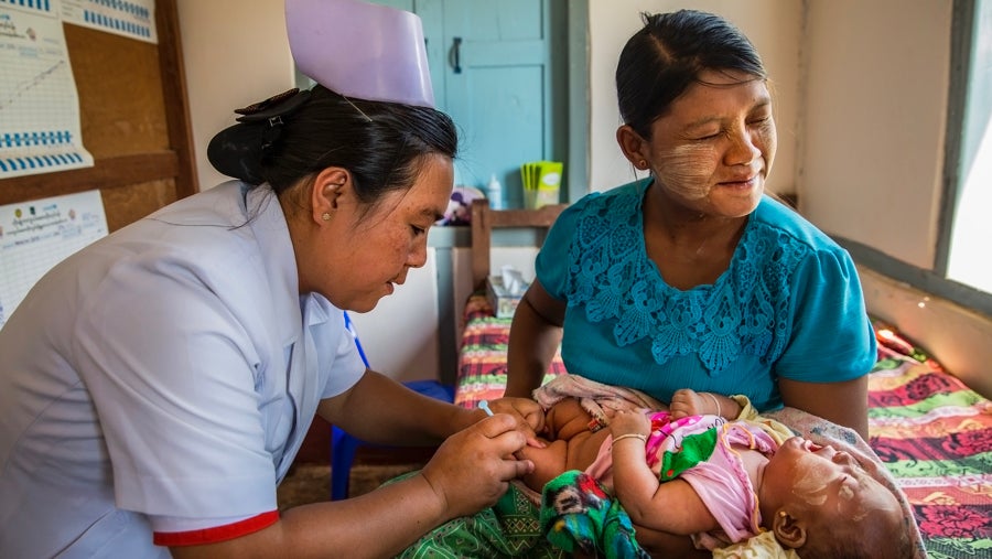 Myanmar:  A mother winces in sympathy pain as Midwife Daw Cho Thae vaccinates her child at the Health Center in Pindaya township. For many women, midwives are the primary point of contact for mothers with the healthcare system and they become trusted voices that help women in the transition to motherhood. ©UN0337712/Nyan Zay Htet