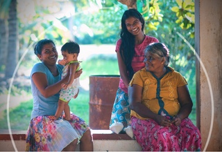 A family of four women and girls of different ages sit outside their porch in Sri Lanka