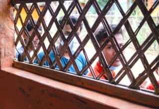 Boys living in the Rohingya camps look inside a room through the blinds
