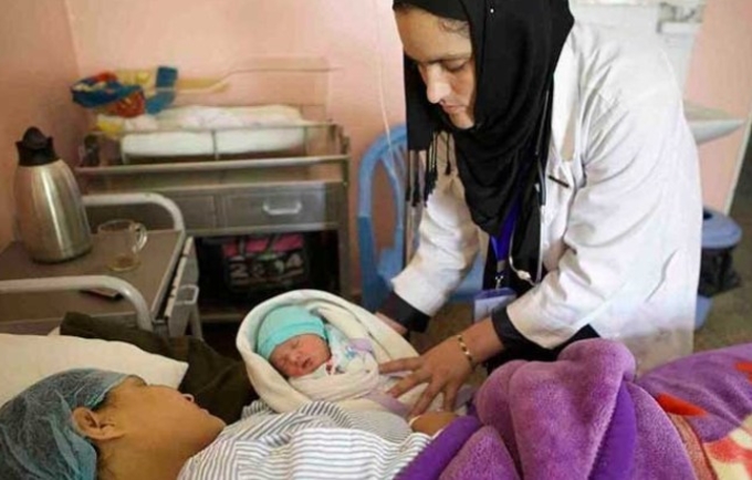 Fahima Nazary, head of midwifery at the CURE Hospital in Kabul, looks over a mother and newborn.