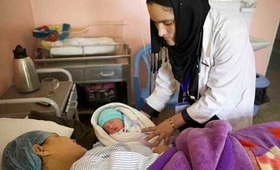 Fahima Nazary, head of midwifery at the CURE Hospital in Kabul, looks over a mother and newborn.