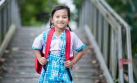 An adolescent girl from Viet Nam smiles while carrying her school bag and travelling to school 