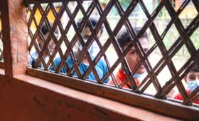 Boys living in the Rohingya camps look inside a room through the blinds