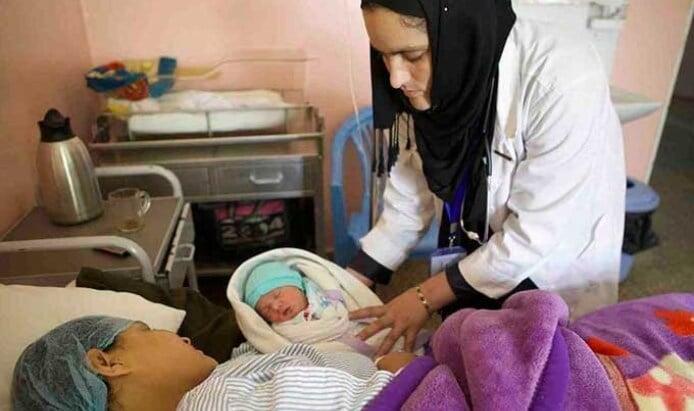 Fahima Nazary, head of midwifery at the CURE Hospital in Kabul, looks over a mother and newborn.