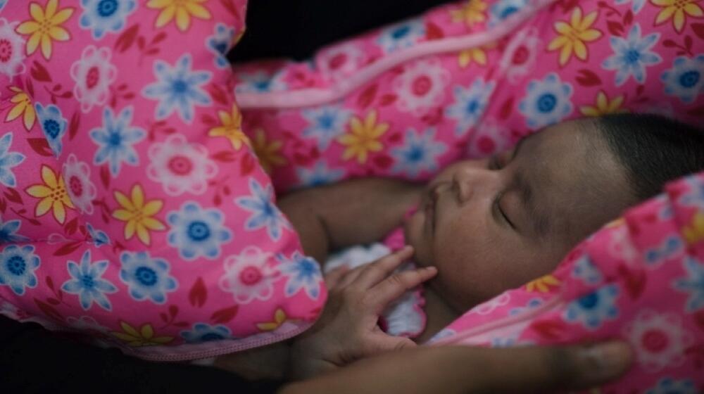 A baby covered in a pink blanket