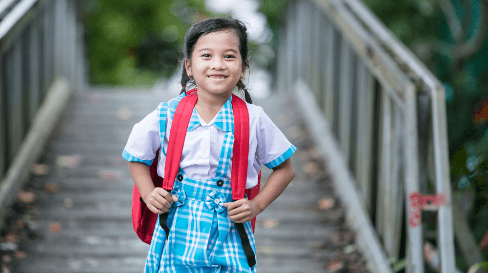 An adolescent girl from Viet Nam smiles while carrying her school bag and travelling to school 