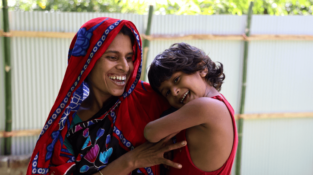 A woman carries her child while both of them laugh 