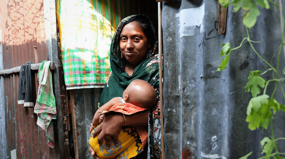 A photo of a mother carrying her infant at a remote village in Bangladesh