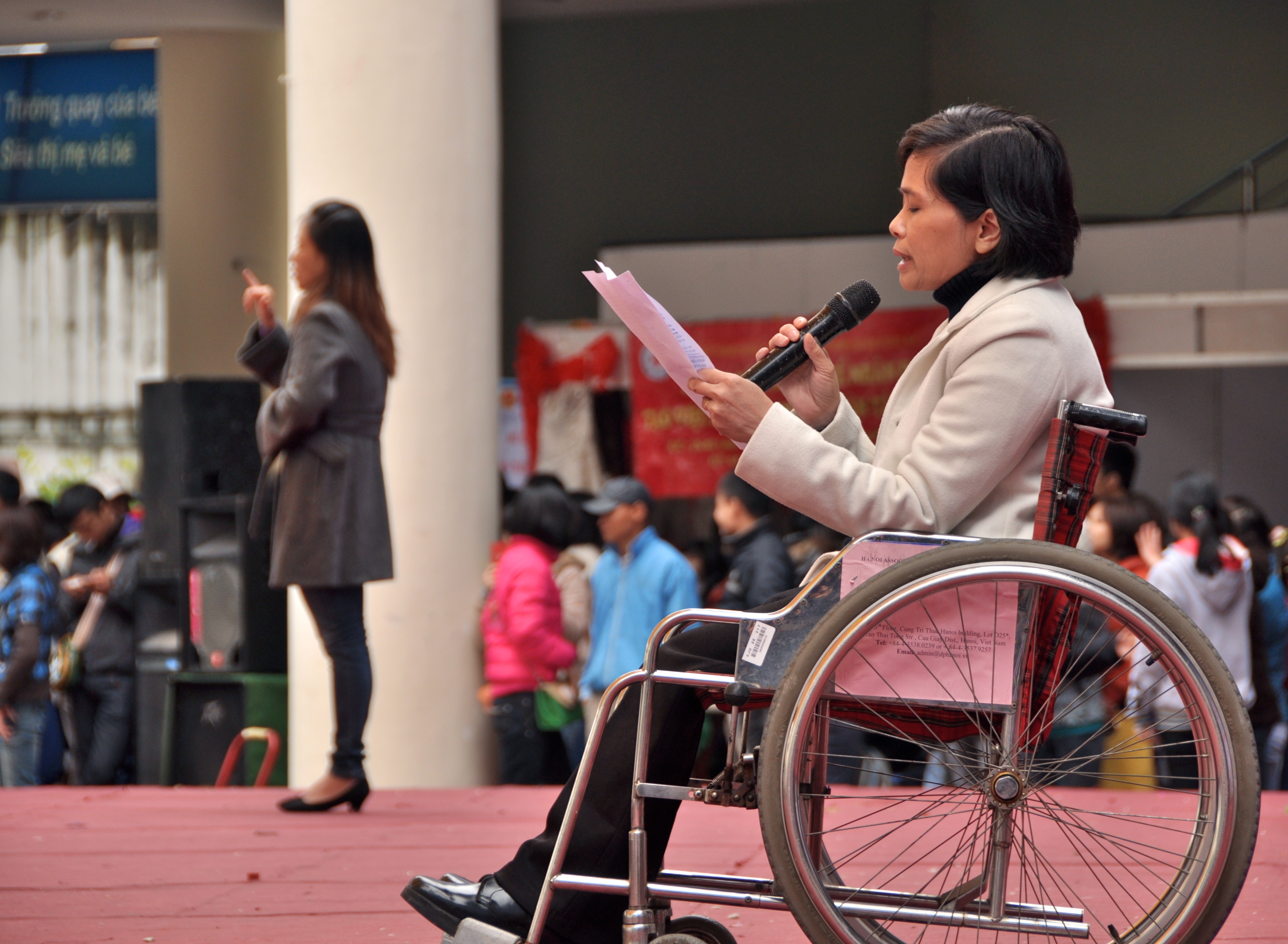 Photo of a woman in a wheelchair holding a microphone adressesing a crowd in Manila, Philippines 
